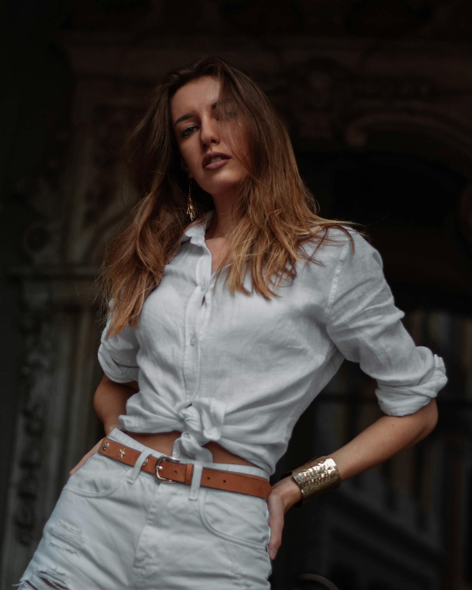 Confident woman in white attire posing stylishly outdoors with charming confidence.