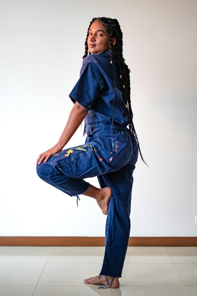 Fashion model with dreadlocks posing in trendy denim outfit indoors, showcasing style and confidence.
