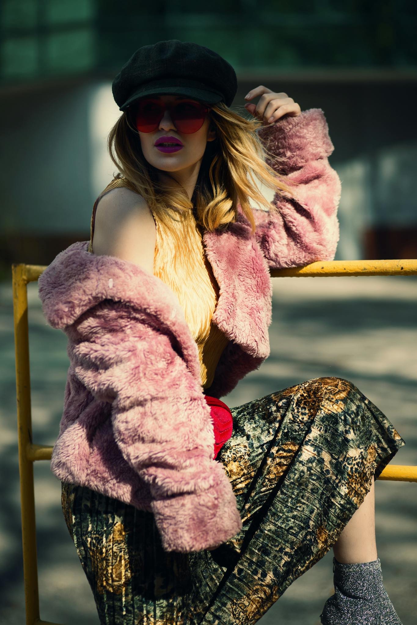 Stylish woman in faux fur coat and hat poses outdoors in a fall setting, showcasing modern fashion.